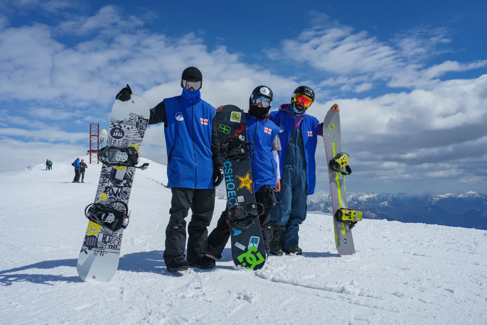 Three riders with their snowboards on the summit ridge above Gudauri