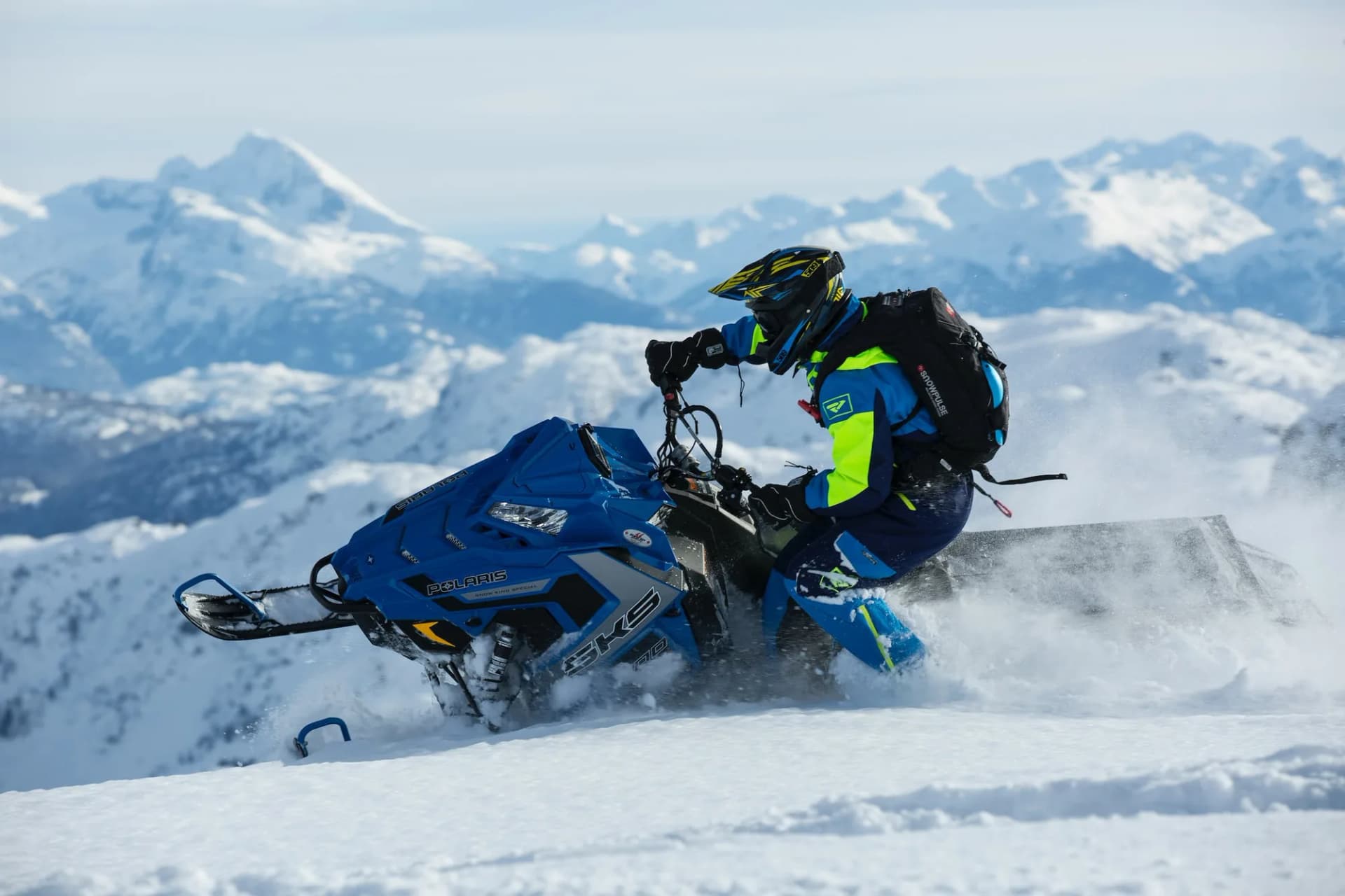 Snowmobile carving through deep powder with the Caucasus range behind